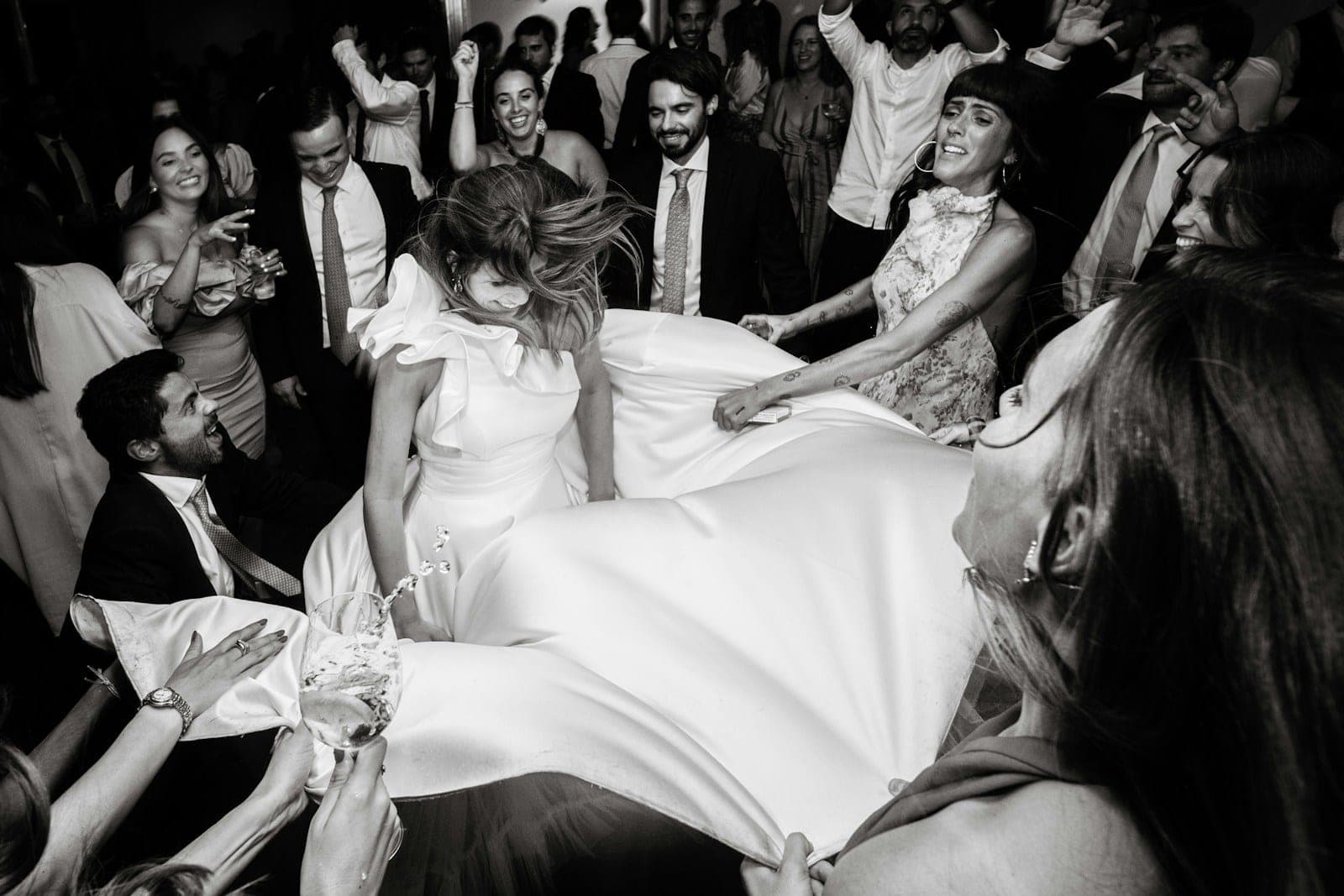 A crowd of wedding guests lifting the bride on the dance floor
